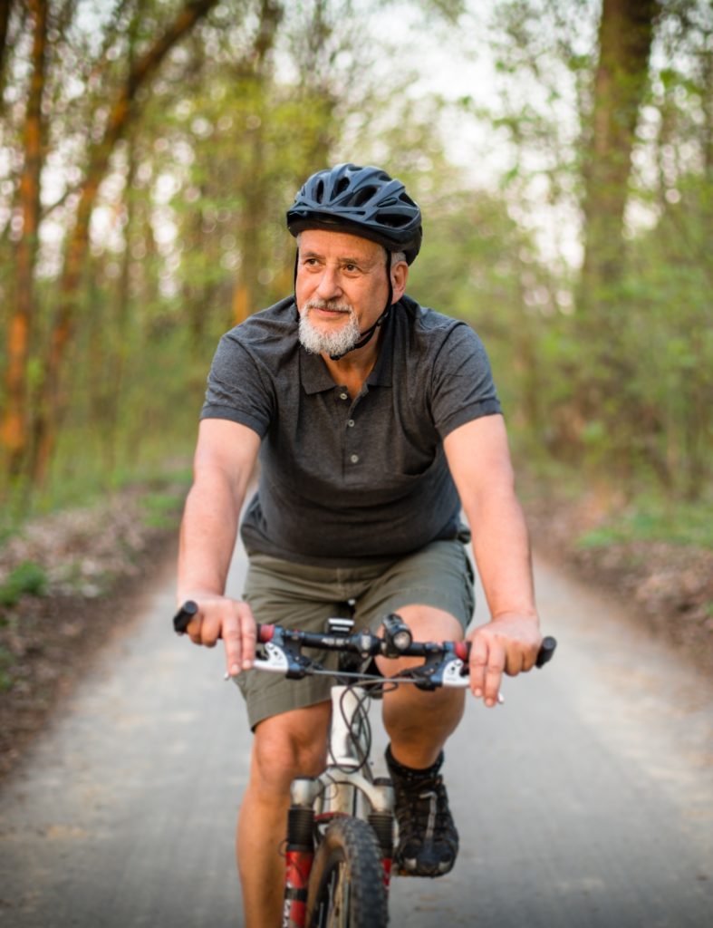 Smiling white man cycling to positively impact his emotional wellbeing