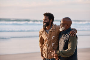 Image of black man and father on the beach representing living with prostate cancer.